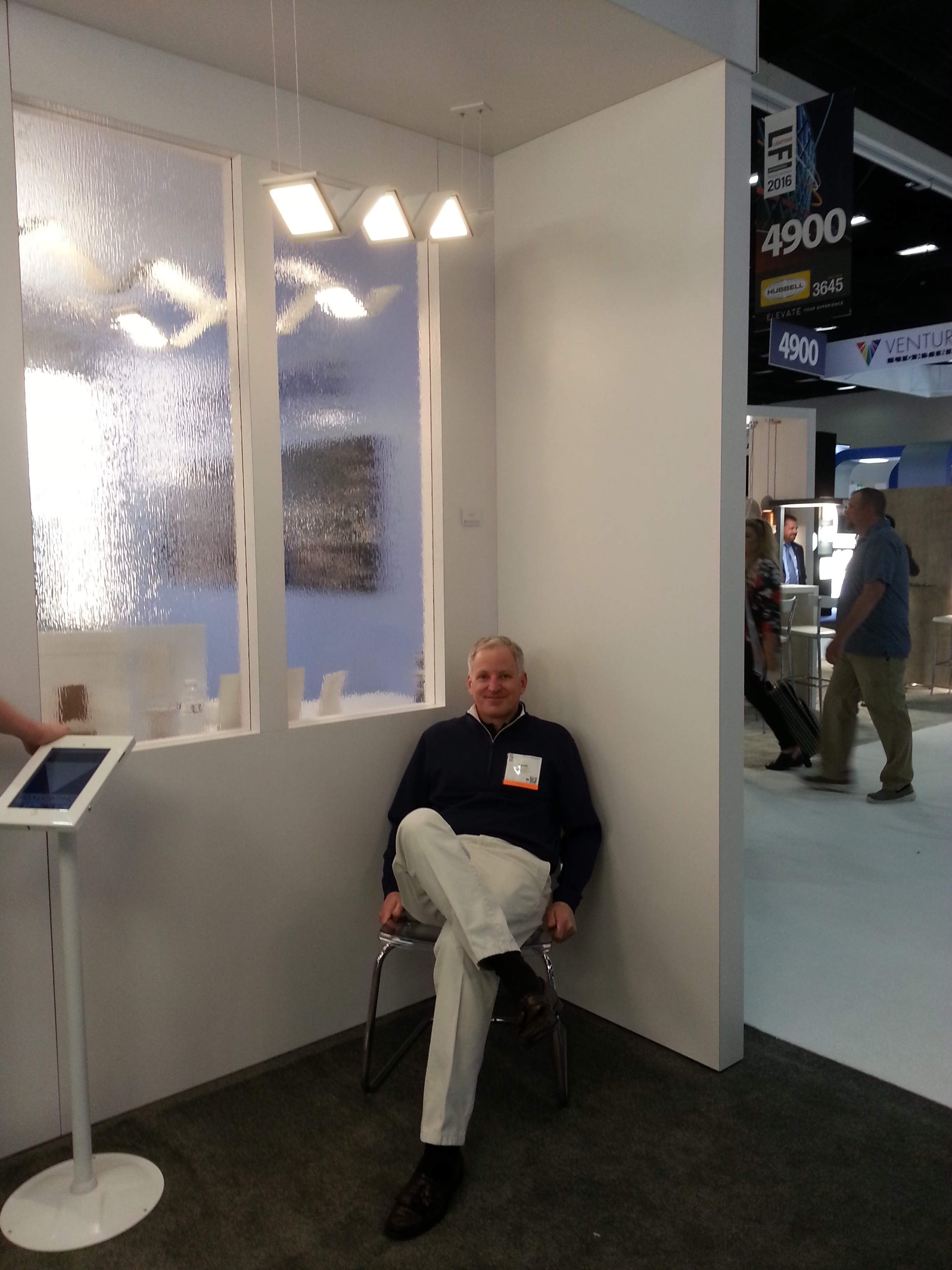 Dave Dejoy sitting under OLED fixture LIMIT by Visa Lighting at Lightfair 2016