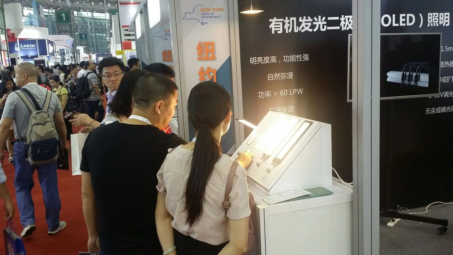 visitors playing with OLED lighting panels at OLEDWorks booth at CIOE in Shenzhen