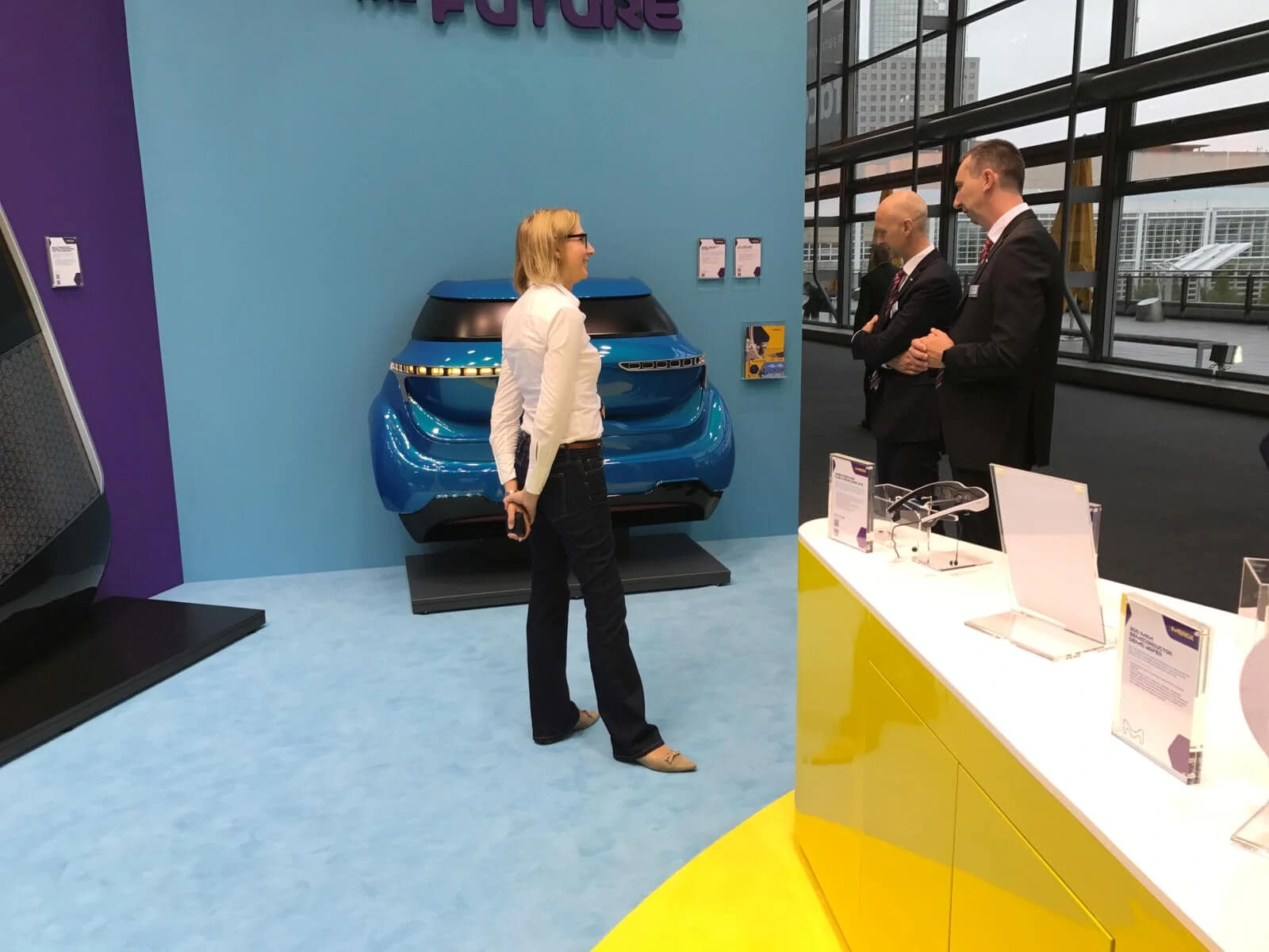 Merck in discussion with visitors of their booth at IAA in front of an OLED rear light demonstrator