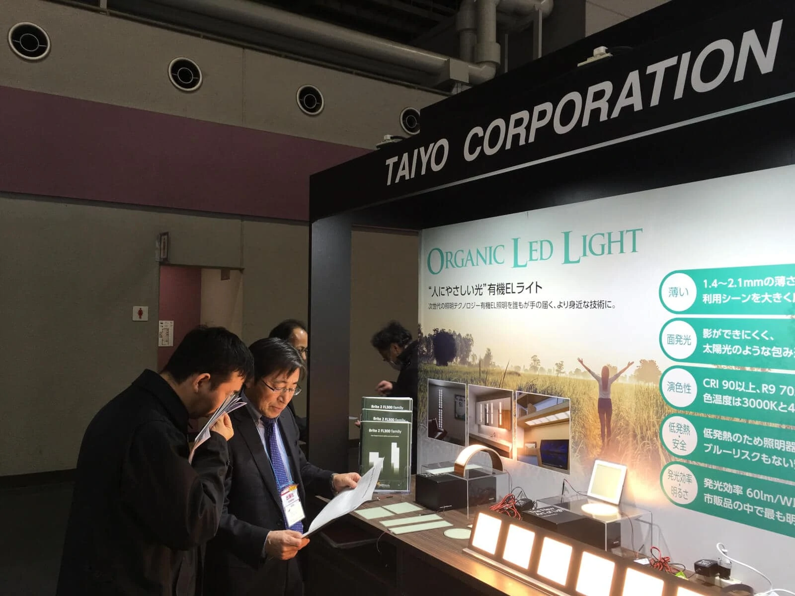 interested visitors at Taiyo booth at Medical Japan reading about OLED lighting
