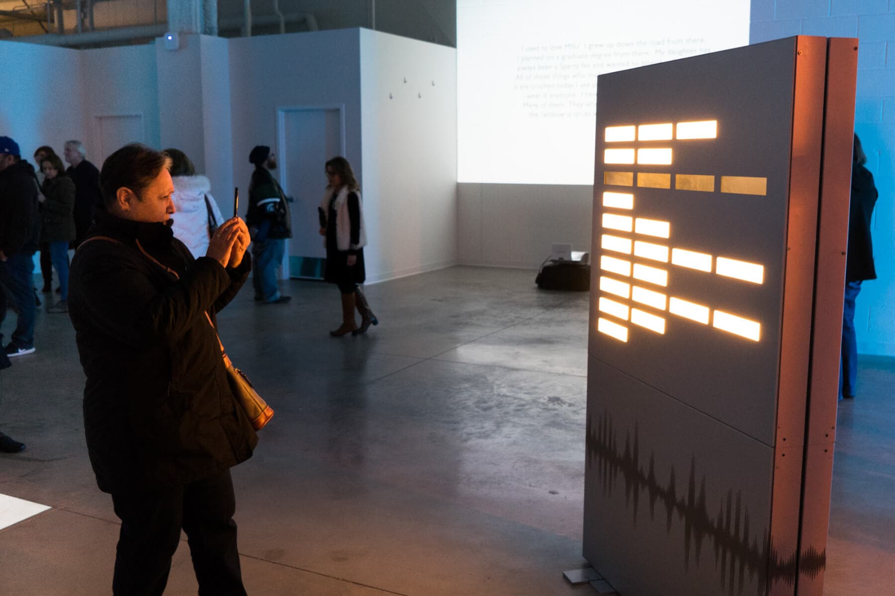 A visitor of the Broad Art Lab takes a picures of the poem Illuminating Survivor Voices