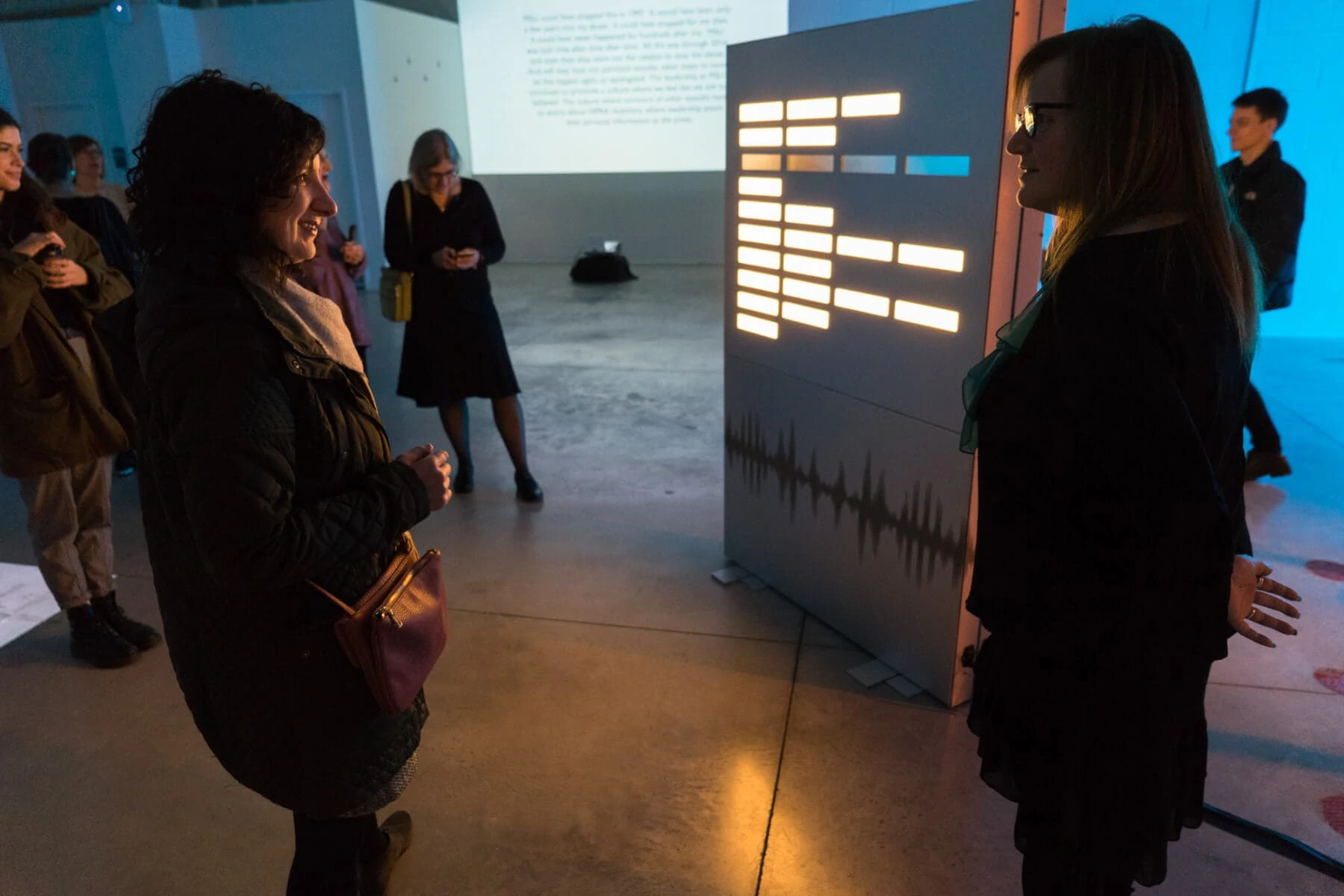 Nancy Dejoy talks to a visitor in front of the poem Illuminating Survivor Voices